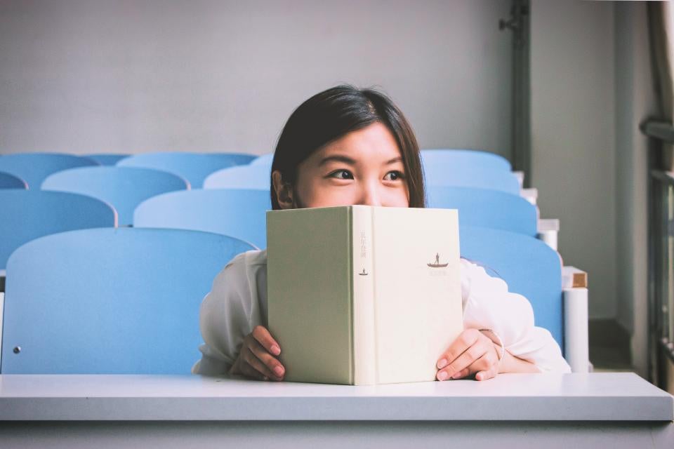 女子学生の学校帳教室の椅子は、幸せな教育リーディング人々を笑顔笑顔