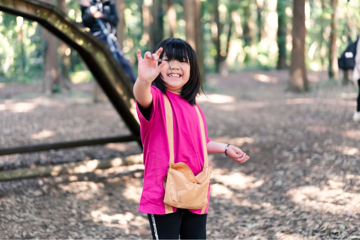 アップサイクルTシャツを着てどんぐり拾いを楽しむ女の子