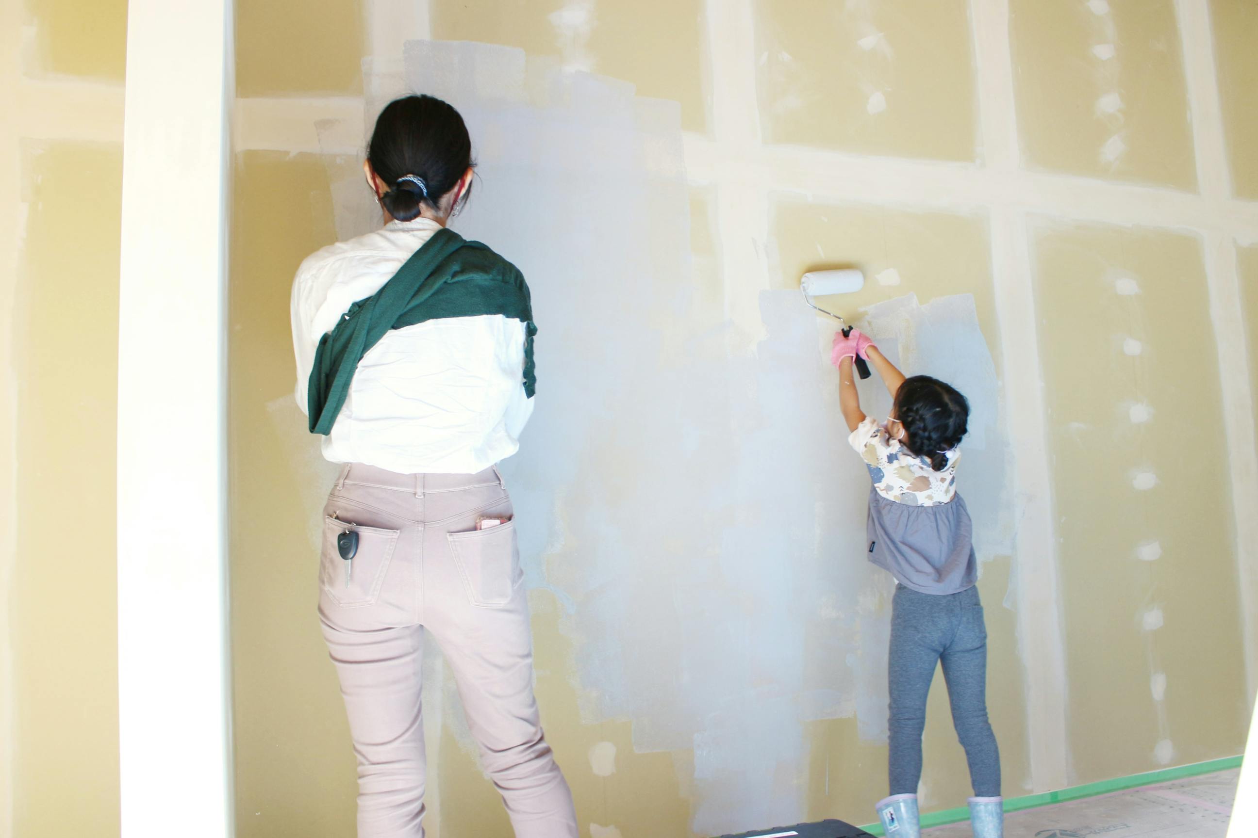 壁塗り風景。壁塗りをする女性（左）と女の子（右）