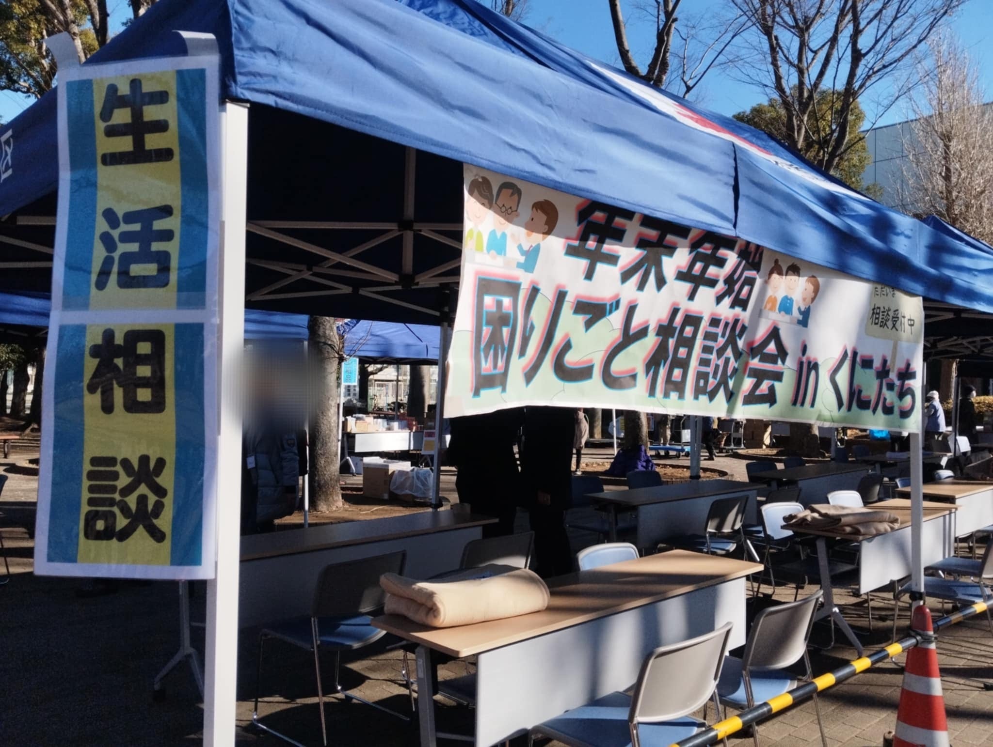 12月29日に開催された「くにたち市 年末年始困りごと相談会」の様子。テントが立てられており、「生活相談」やイベント名の看板が貼られている。