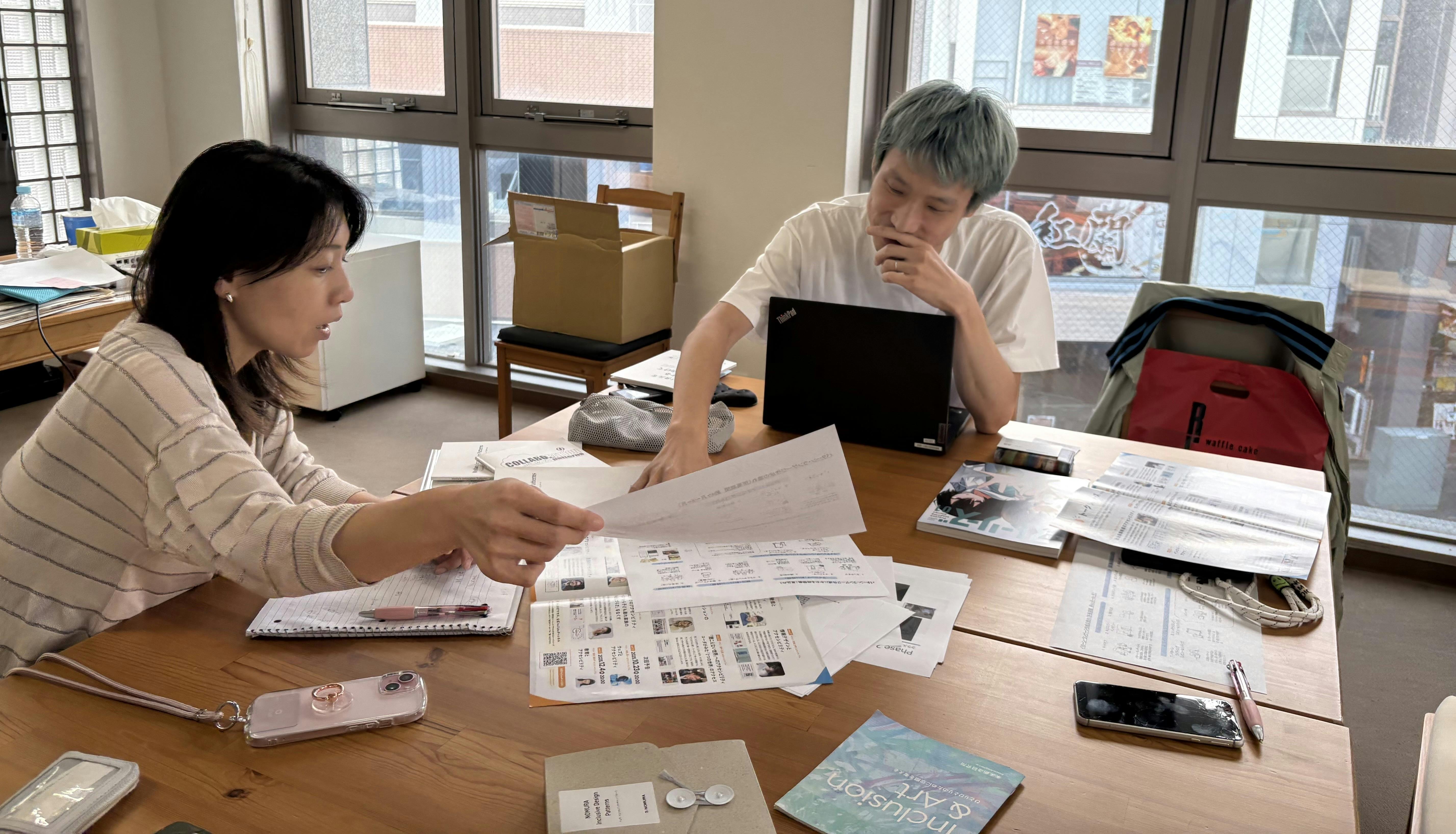 事務所のデスクで書類や過去のパターン・ランゲージの成果物を広げながら、正井さんと榎本が話している