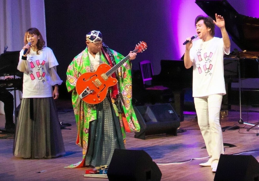 左　麻生かほ里　片腕のギタリスト輝彦　石井一孝の３人の写真