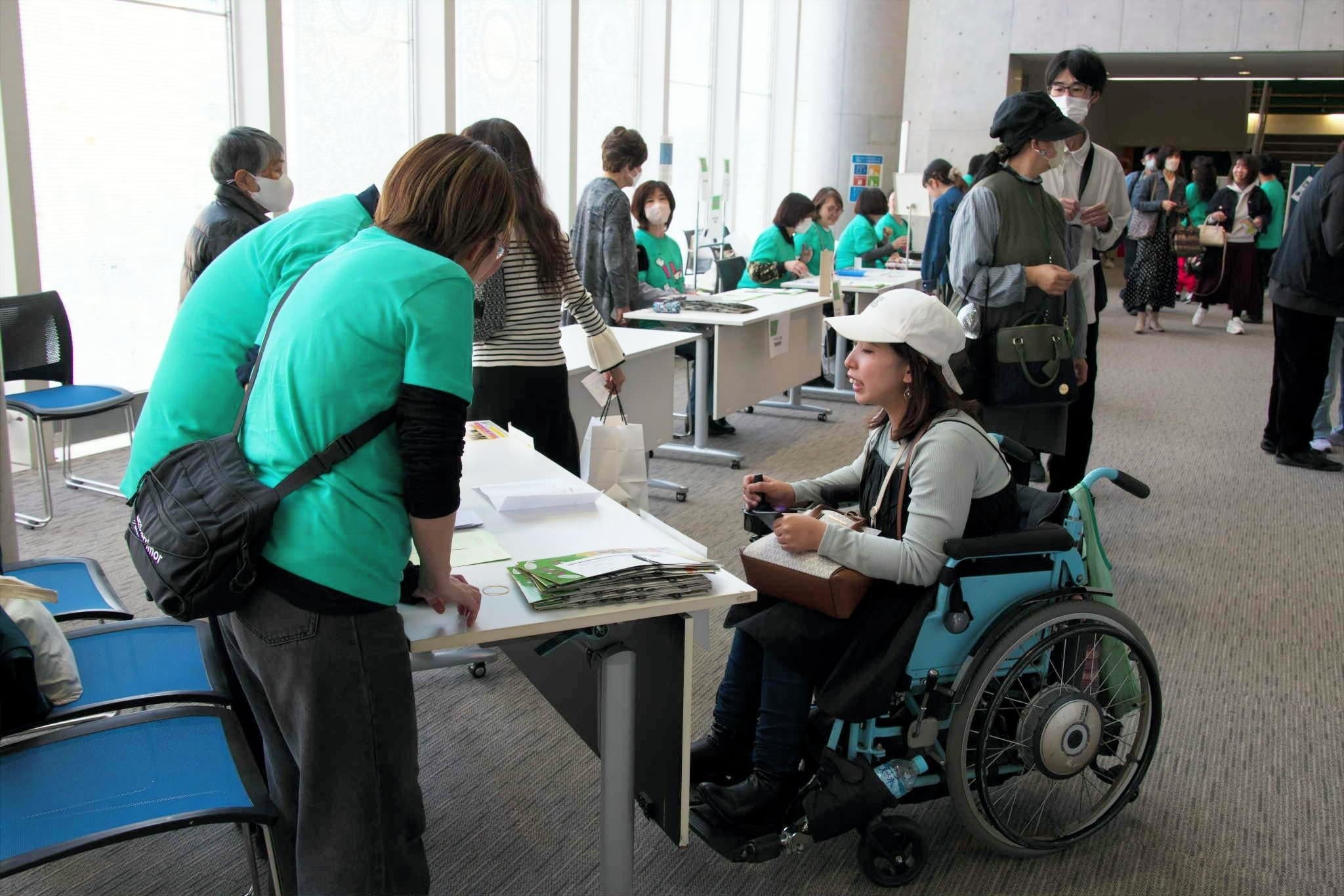 車椅子の女性に対応する受付スタッフの写真