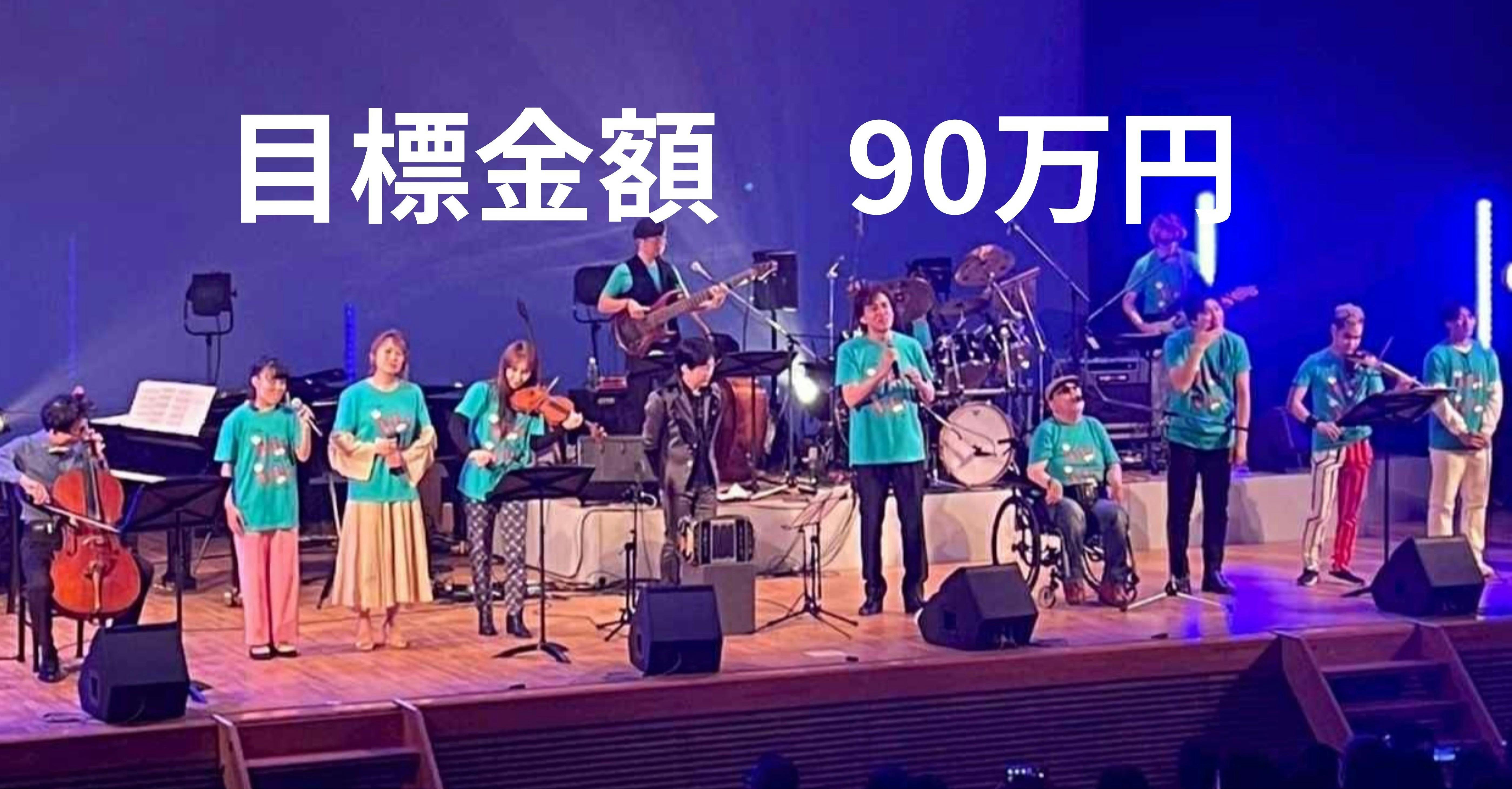 目標金額90万円　青い背景の舞台にそろうアーティスト達