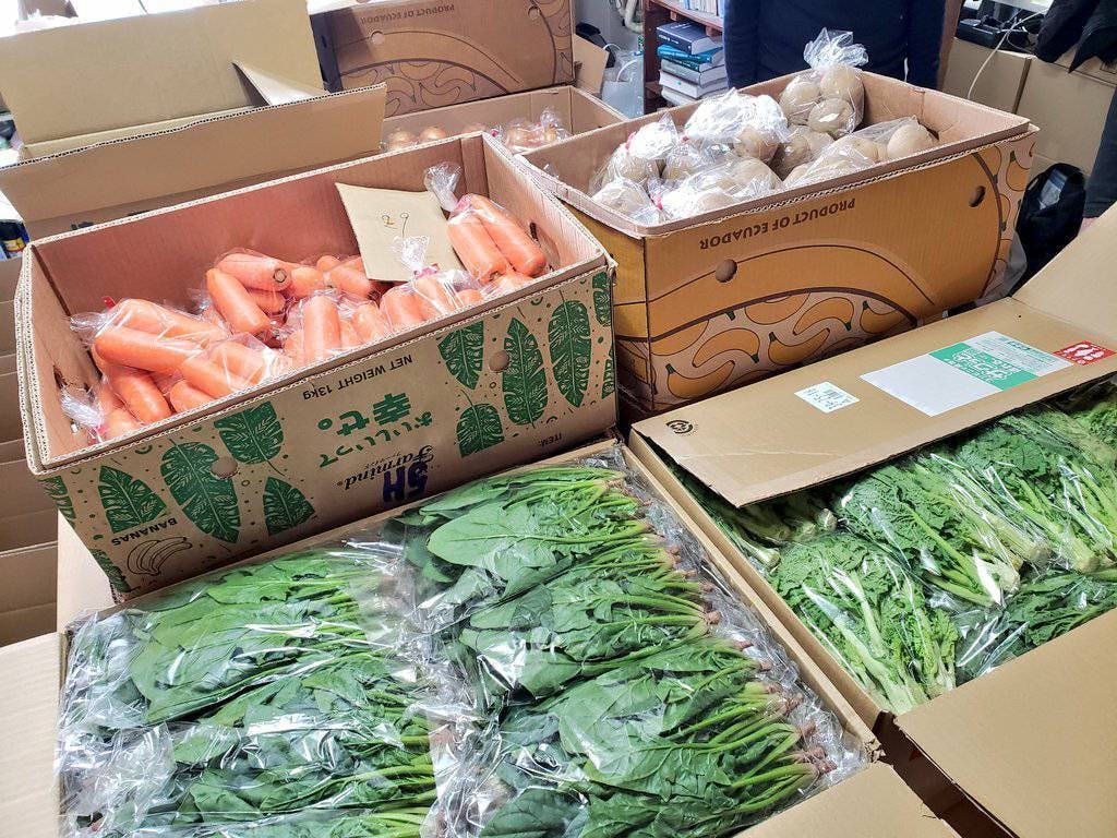 食料支援の梱包作業の様子。にんじんやじゃがいもなど、さまざまな野菜がダンボールに詰められている。