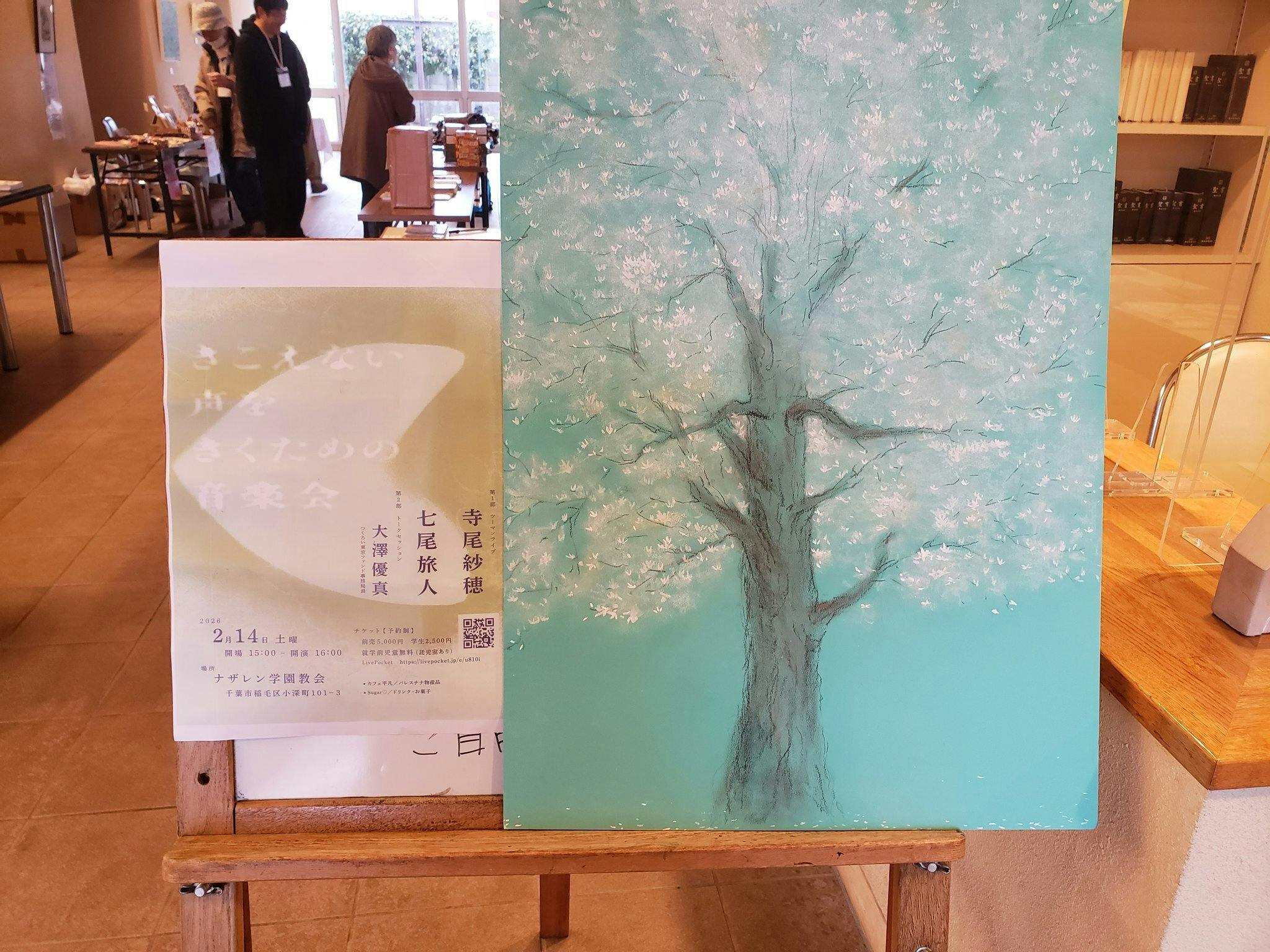 イベント会場の様子。フライヤーが印刷されている。その隣に大きな木の絵がかけられている。