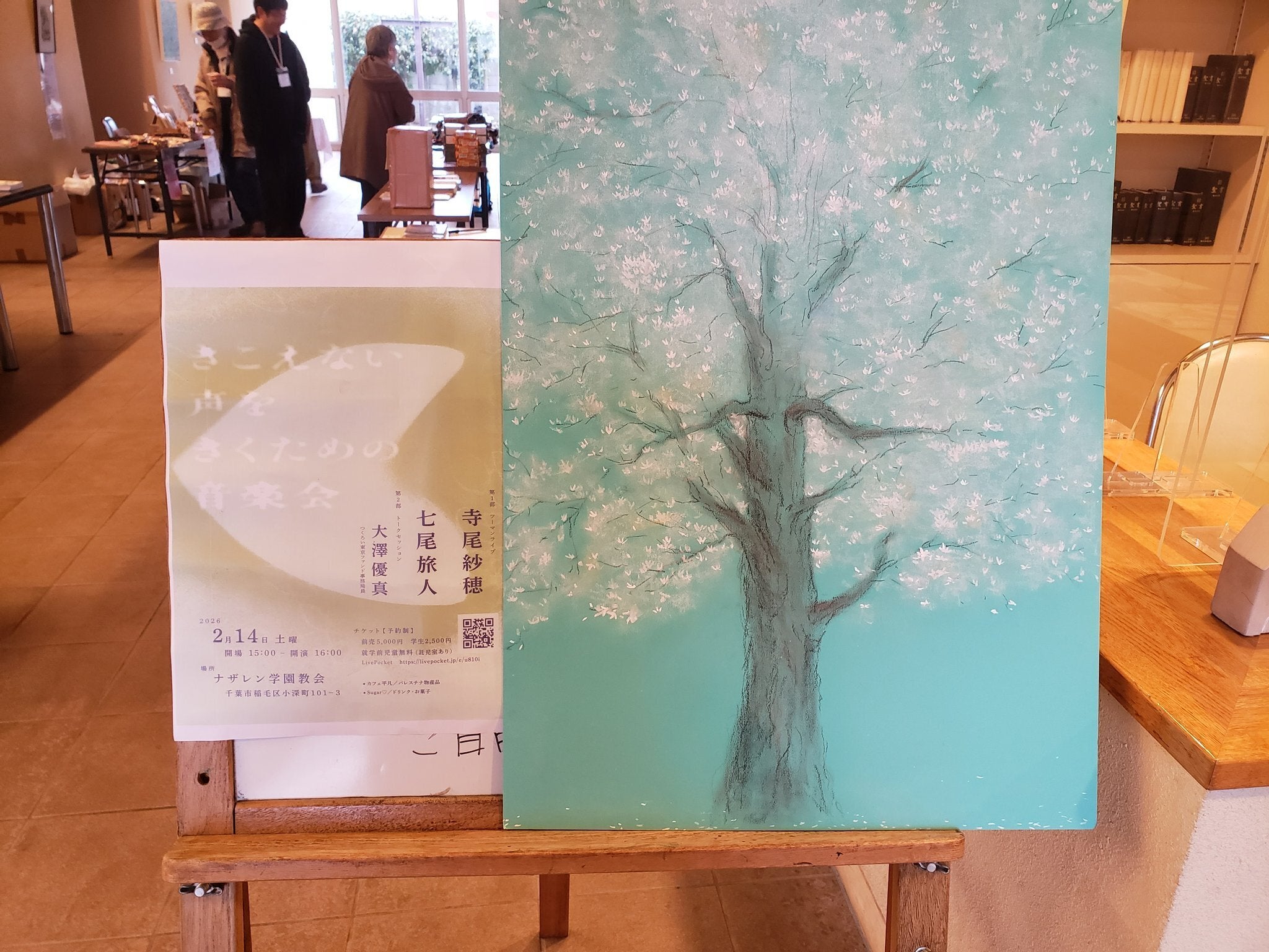 イベント会場の様子。フライヤーが印刷されている。その隣に大きな木の絵がかけられている。