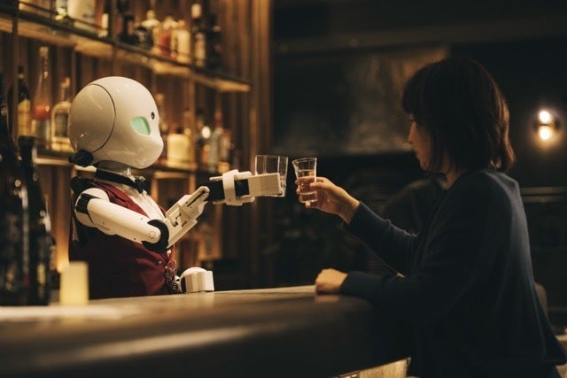 バーのカウンター越しに、女性のお客さんと乾杯をするOriHime-D